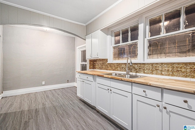 kitchen with white cabinets, sink, crown molding, tasteful backsplash, and butcher block counters