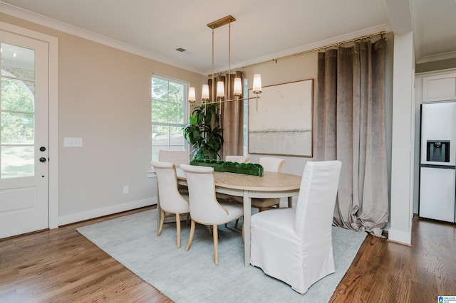 dining area featuring hardwood / wood-style floors, an inviting chandelier, and ornamental molding