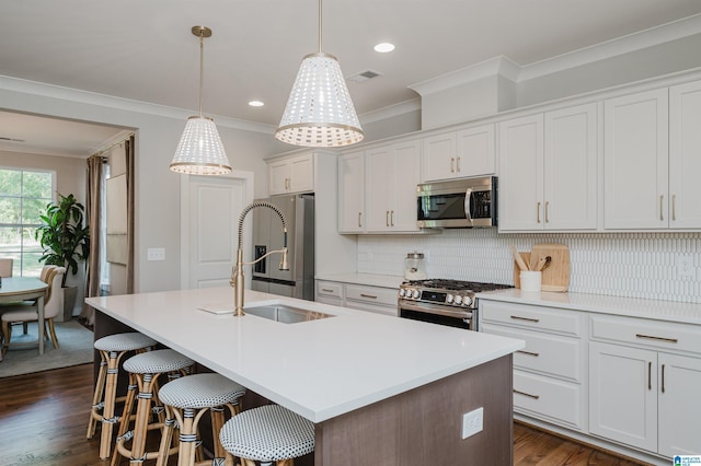 kitchen with sink, hanging light fixtures, a center island with sink, white cabinets, and appliances with stainless steel finishes