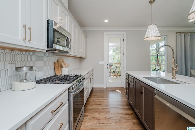 kitchen featuring white cabinetry, sink, stainless steel appliances, and decorative light fixtures