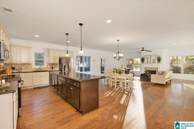 kitchen with a center island, stainless steel appliances, light hardwood / wood-style floors, decorative light fixtures, and ceiling fan with notable chandelier