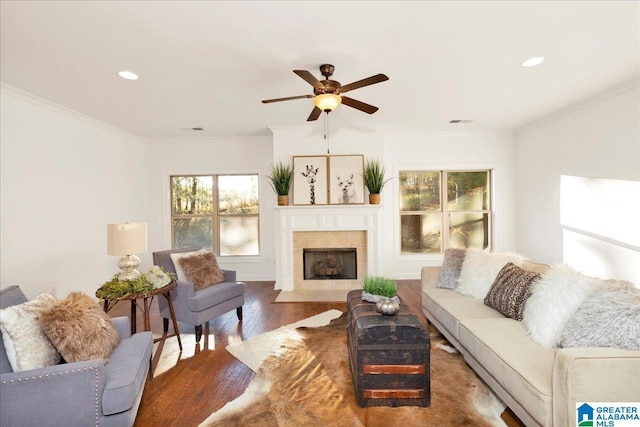 living room with a fireplace, dark hardwood / wood-style floors, ceiling fan, and crown molding