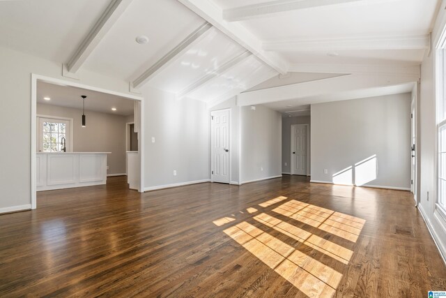 unfurnished living room with vaulted ceiling with beams, dark hardwood / wood-style floors, and sink