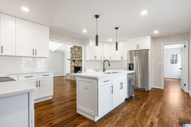 kitchen with pendant lighting, dark wood-type flooring, white cabinets, decorative backsplash, and stainless steel appliances