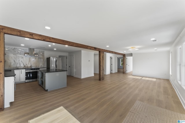 unfurnished living room with hardwood / wood-style floors and beam ceiling