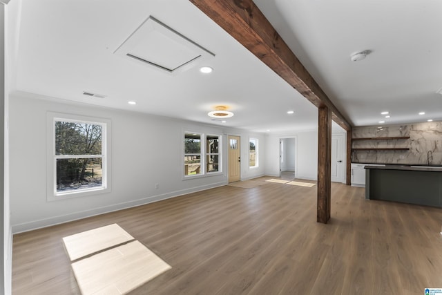 unfurnished living room featuring beamed ceiling, bar area, and dark hardwood / wood-style floors