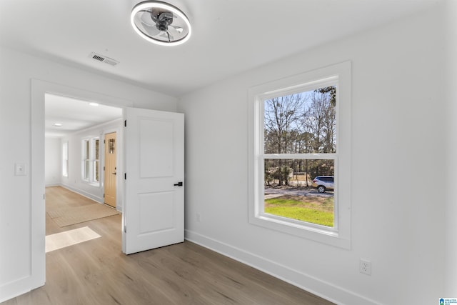 empty room with a wealth of natural light and light hardwood / wood-style floors