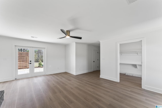 unfurnished bedroom with dark wood-type flooring, french doors, a spacious closet, ceiling fan, and access to exterior