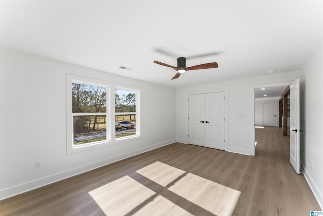 unfurnished bedroom featuring dark wood-type flooring, ceiling fan, and a closet