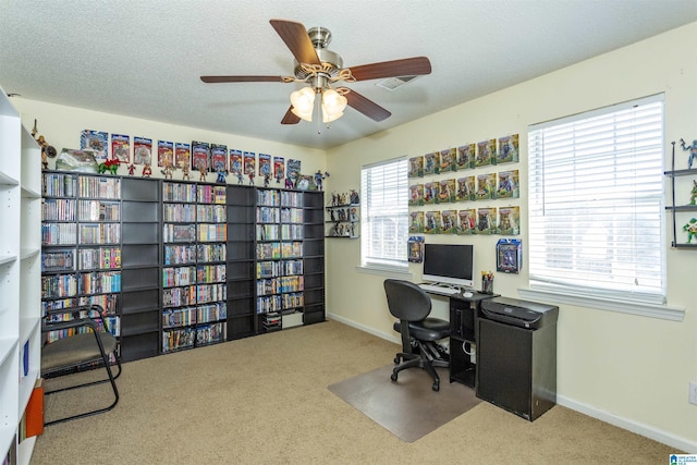 carpeted office space with a textured ceiling and ceiling fan