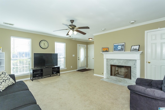 living room featuring a high end fireplace, light carpet, ceiling fan, and ornamental molding