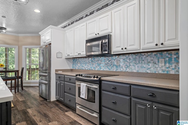 kitchen featuring white cabinets, decorative backsplash, stainless steel appliances, and a textured ceiling