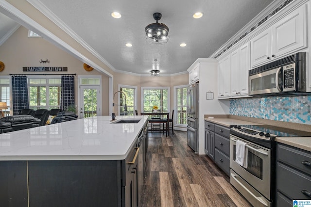 kitchen featuring white cabinetry, sink, stainless steel appliances, dark hardwood / wood-style floors, and a center island with sink