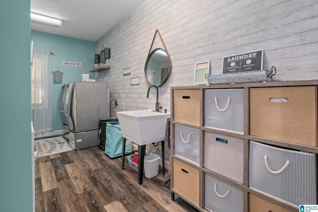 interior space with sink, a textured ceiling, dark wood-type flooring, and wood walls