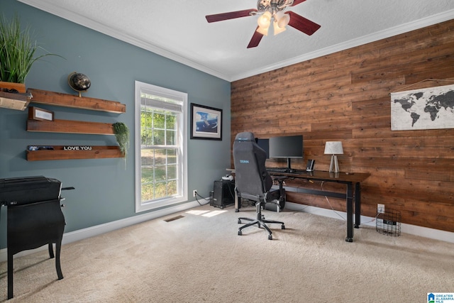 home office featuring wooden walls, crown molding, ceiling fan, and light carpet