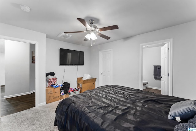 bedroom with connected bathroom, dark carpet, and ceiling fan