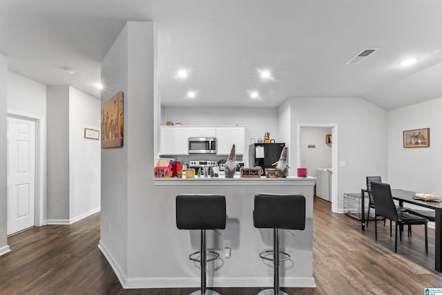 kitchen with a breakfast bar, lofted ceiling, white cabinets, washer / dryer, and stainless steel appliances