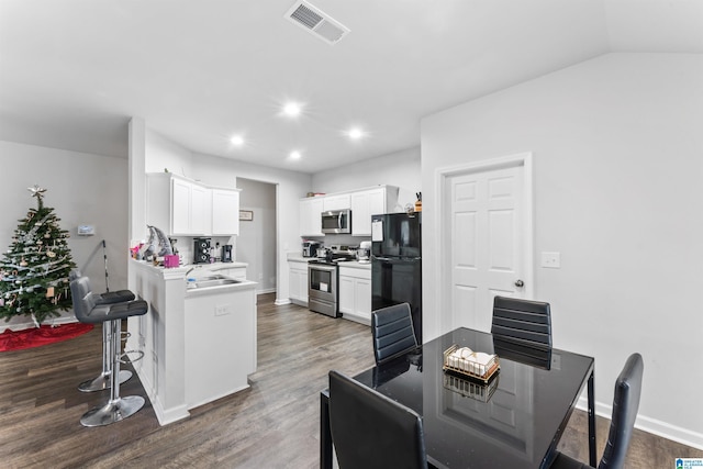 kitchen with dark hardwood / wood-style flooring, a breakfast bar, stainless steel appliances, sink, and white cabinets