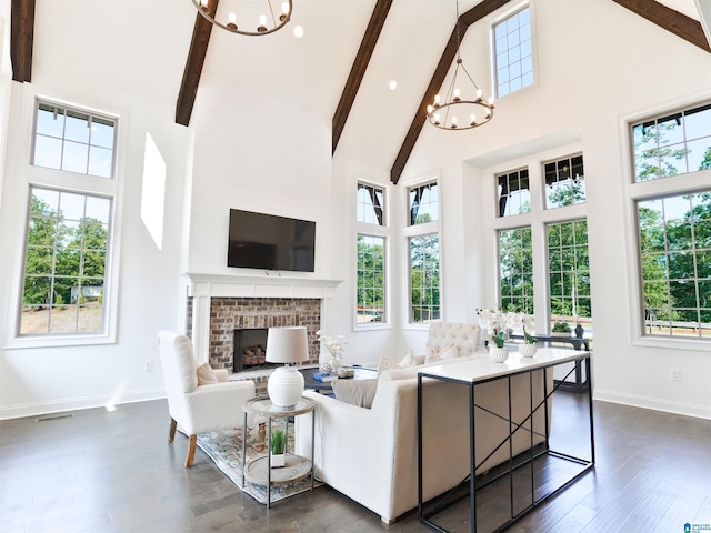 living room featuring beamed ceiling, high vaulted ceiling, a chandelier, and a brick fireplace