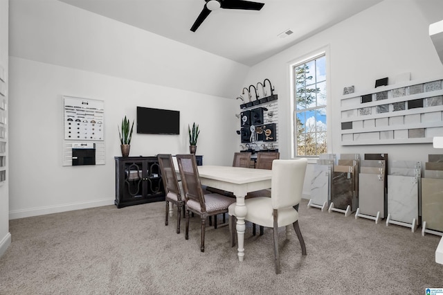 carpeted dining space with ceiling fan and lofted ceiling