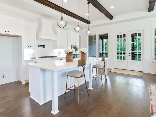 kitchen with stainless steel appliances, a kitchen island, white cabinetry, and custom exhaust hood