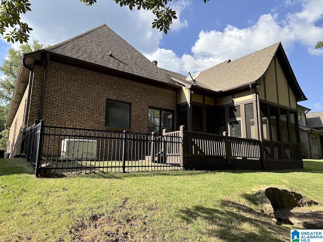 back of house featuring a yard, a wooden deck, and a sunroom