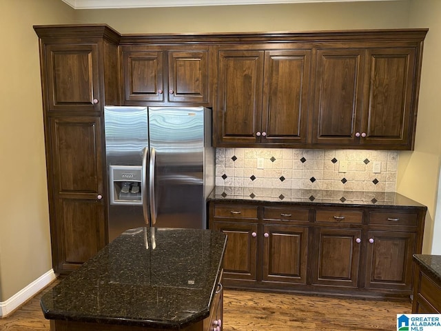 kitchen featuring dark brown cabinetry, tasteful backsplash, stainless steel refrigerator with ice dispenser, dark stone counters, and light hardwood / wood-style floors