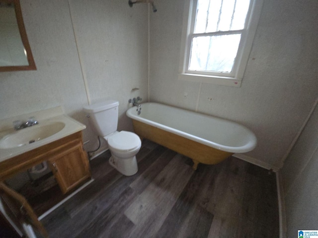 bathroom featuring hardwood / wood-style flooring, a washtub, toilet, and vanity