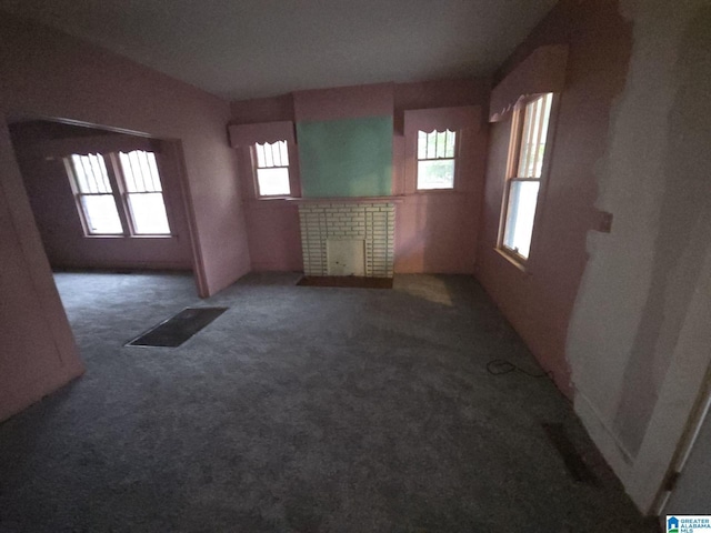 empty room featuring a fireplace and dark colored carpet