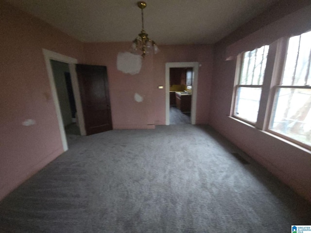 carpeted empty room with a notable chandelier