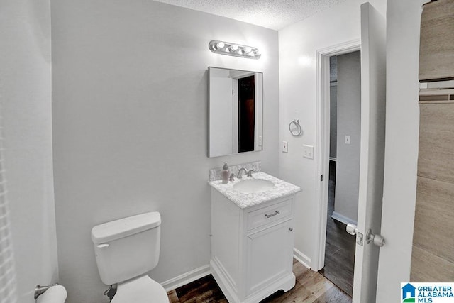 bathroom featuring hardwood / wood-style floors, vanity, toilet, and a textured ceiling