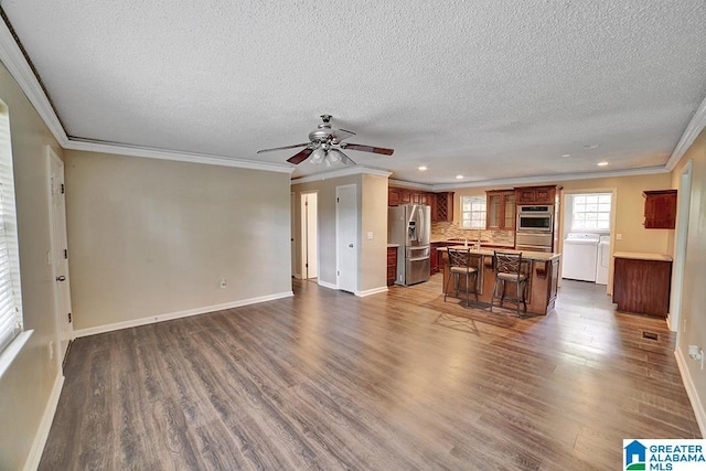 kitchen with a center island, backsplash, ornamental molding, a kitchen bar, and stainless steel appliances