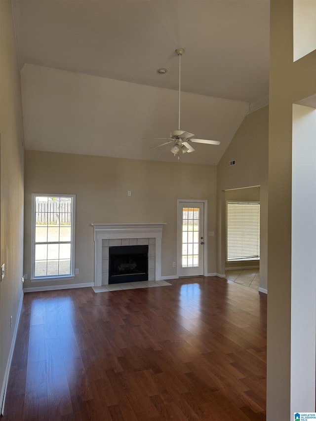 unfurnished living room featuring a wealth of natural light, ceiling fan, a tile fireplace, and dark hardwood / wood-style floors