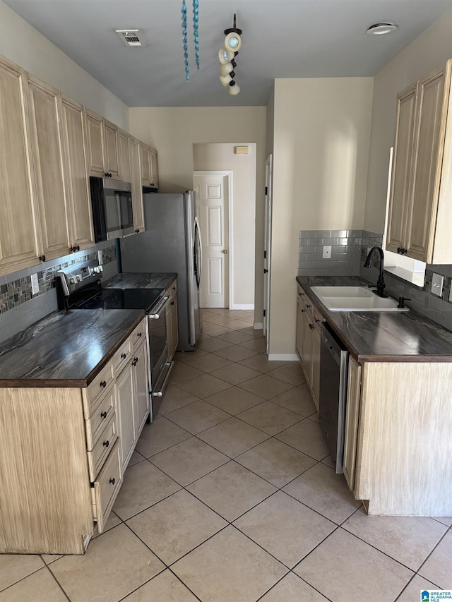 kitchen with backsplash, sink, light tile patterned floors, and stainless steel appliances