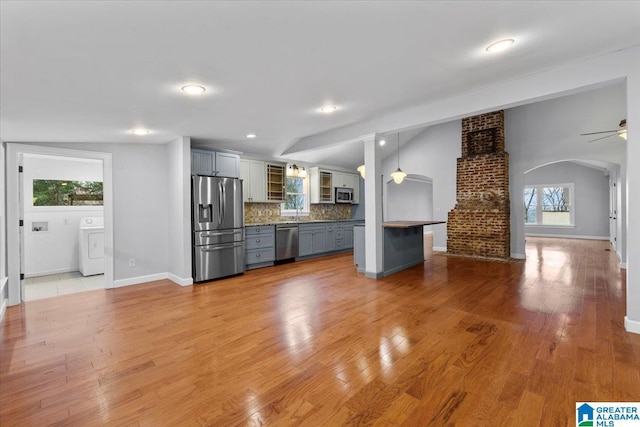 kitchen with gray cabinets, vaulted ceiling, washer / clothes dryer, backsplash, and stainless steel appliances