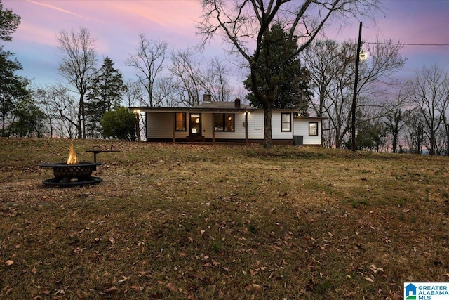 view of front of home with an outdoor fire pit and a yard