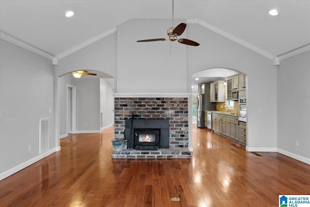 unfurnished living room featuring hardwood / wood-style flooring, ornamental molding, a fireplace, and ceiling fan