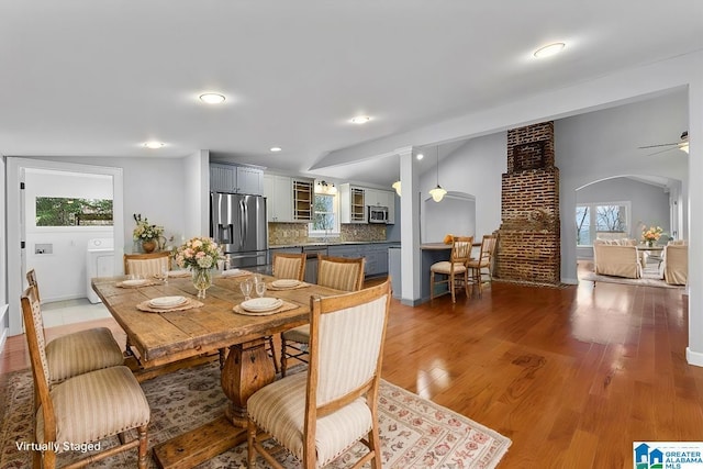 dining area featuring hardwood / wood-style flooring, lofted ceiling, washer / dryer, and decorative columns