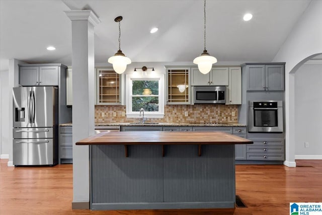 kitchen featuring pendant lighting, appliances with stainless steel finishes, butcher block counters, and vaulted ceiling