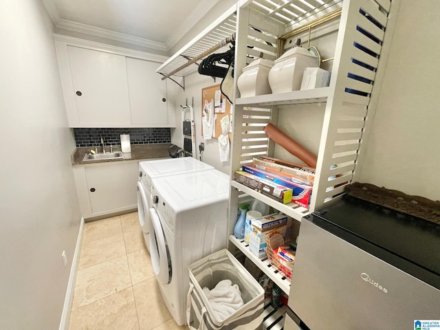 clothes washing area featuring cabinets, sink, ornamental molding, light tile patterned floors, and washing machine and clothes dryer