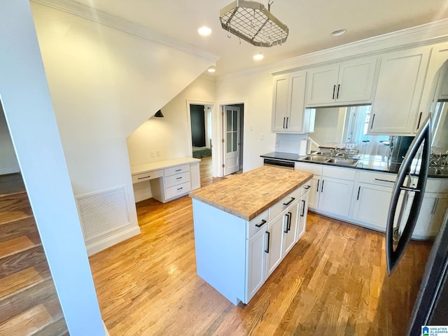 kitchen featuring a center island, crown molding, sink, and white cabinets