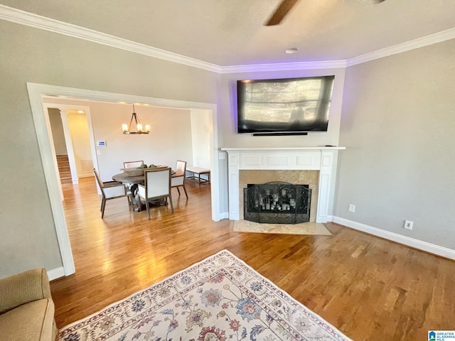 living room featuring wood-type flooring, ceiling fan with notable chandelier, and ornamental molding