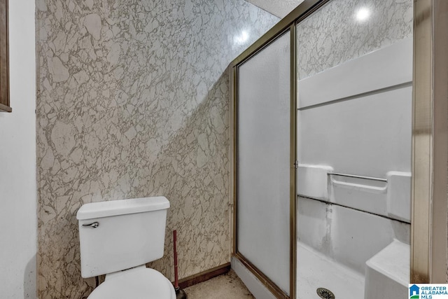 bathroom featuring toilet and a shower with shower door