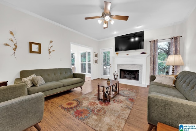 living room featuring ceiling fan, crown molding, a high end fireplace, and wood-type flooring