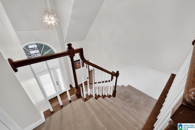 staircase featuring a chandelier and vaulted ceiling