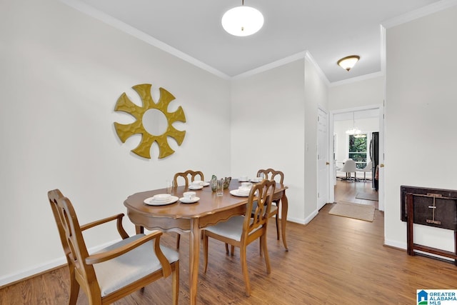 dining area with crown molding, light hardwood / wood-style flooring, and a chandelier