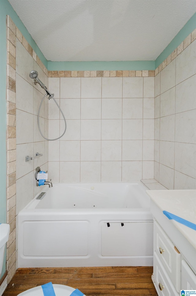 full bathroom featuring hardwood / wood-style floors, a textured ceiling, toilet, vanity, and tiled shower / bath