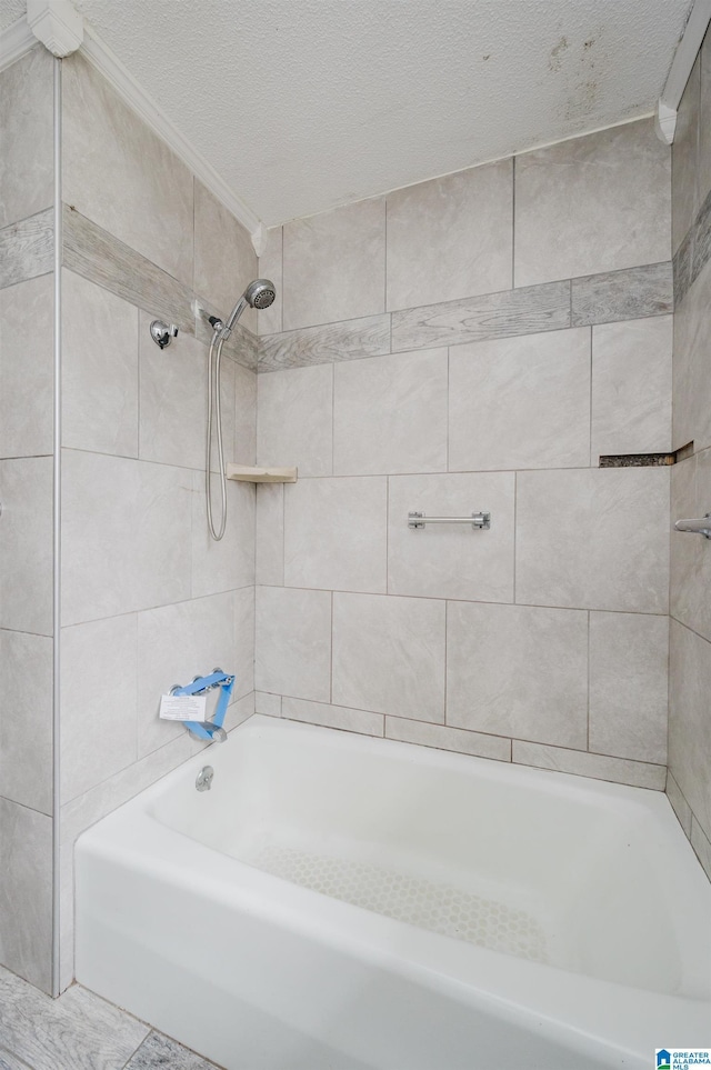 bathroom featuring a textured ceiling and tiled shower / bath combo