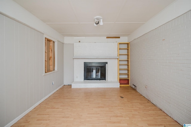 unfurnished living room featuring a fireplace, hardwood / wood-style floors, and brick wall