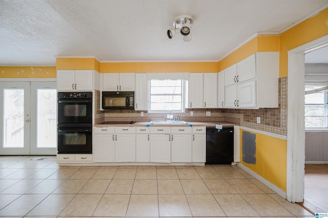 kitchen featuring backsplash, sink, black appliances, light tile patterned floors, and white cabinets